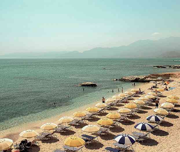 En strand med parasoller och solstolar vid havet. (AI-genererad text)