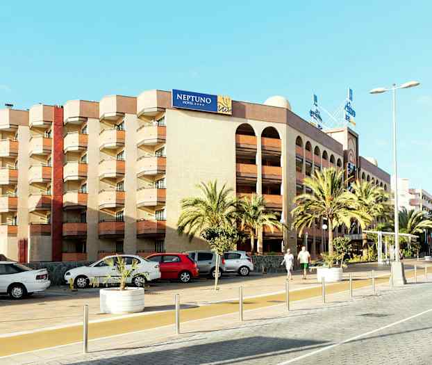 En flerfärgad byggnad med en skylt med texten "NEPTUNO HOTEL", omgiven av palmer och parkerade bilar. (AI-genererad text)