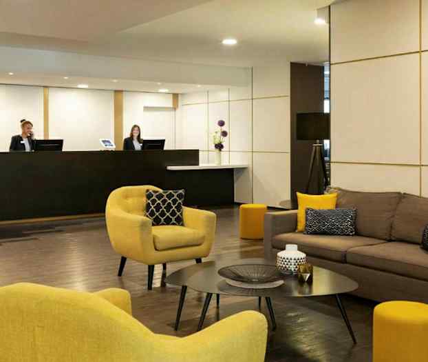 Ett hotellobby med soffor och fåtöljer samt ett receptionsområde. (AI-genererad text)