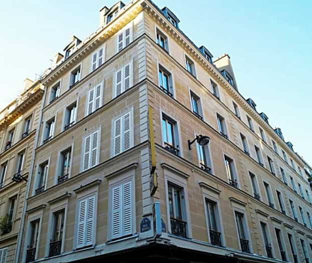 Ett hörnhus med flera våningar och fönsterluckor. (AI-genererad text)