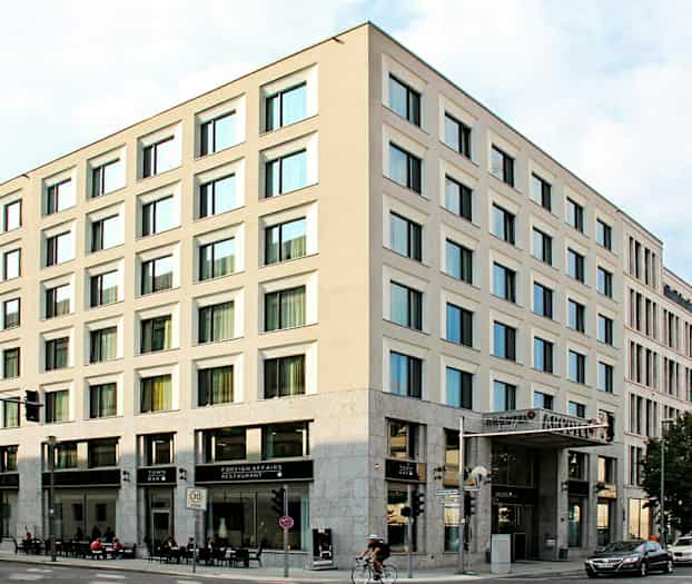Ett hörnhus med moderna fasader och stora fönster, med restaurang och bar på bottenvåningen. (AI-genererad text)