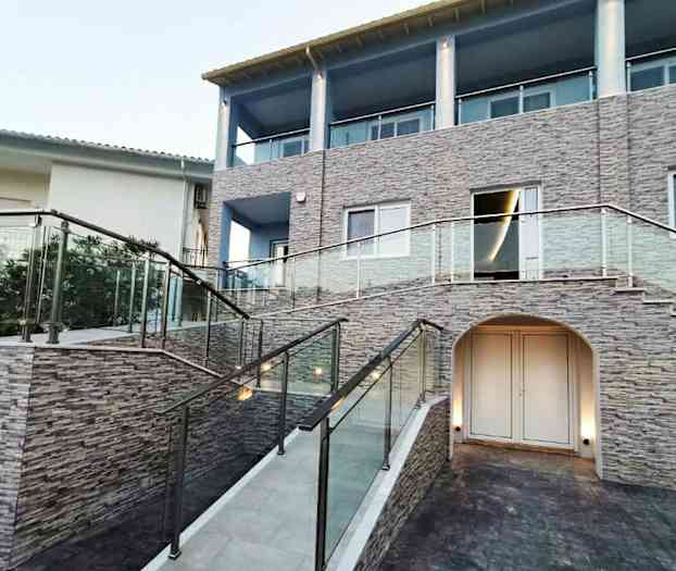 En byggnad med stenfasad, glasräcken och en trappa. (AI-genererad text)