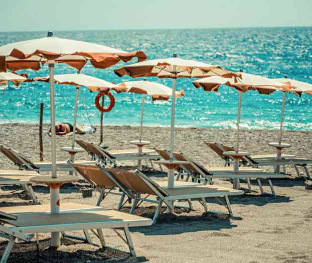 Solstolar och parasoller på en strand vid havet. (AI-genererad text)