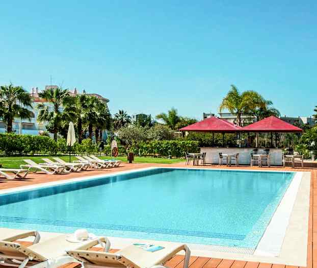 Utomhuspool med solstolar och parasoller, omgiven av grönska. (AI-genererad text)