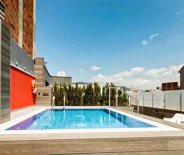 En pool på en takterrass med träd och byggnader i bakgrunden. (AI-genererad text)