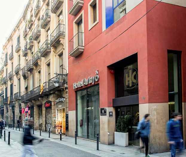 En stadsgata med människor som går förbi, fasader av byggnader och en entré till ett hotell. (AI-genererad text)