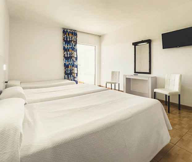 Ett hotellrum med tre enkelsängar, ett skrivbord med spegel, två stolar och en väggmonterad TV. (AI-genererad text)