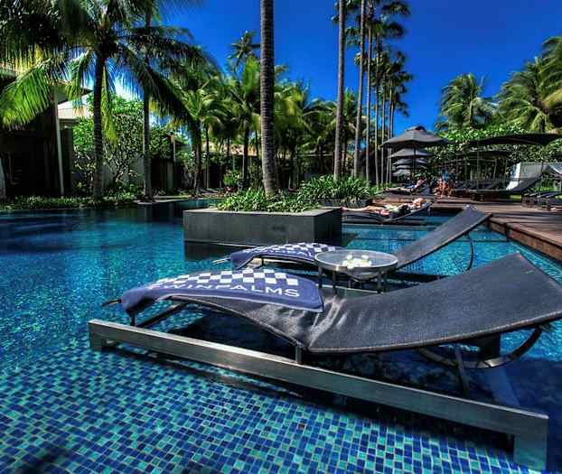 Bild av solstolar vid en pool omgiven av palmer. (AI-genererad text)