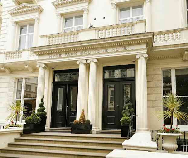 Framsidan av ett boutiquehotell med huvudingång och pelare. (AI-genererad text)