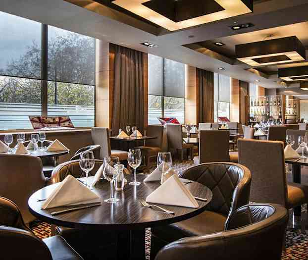 Ett elegant restaurang med dukade bord med vita servetter och vinglas. (AI-genererad text)