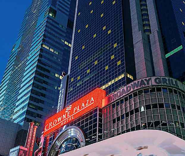 En bild av en hög byggnad med skyltar i neon som visar "Crowne Plaza" och "Broadway Grill". (AI-genererad text)