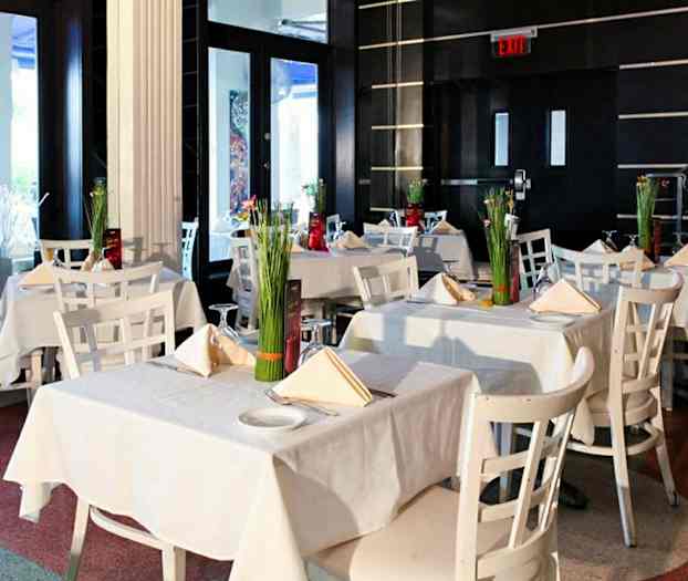 Ett elegant restaurangområde med vita bord och stolar dekorerade med blommor. (AI-genererad text)