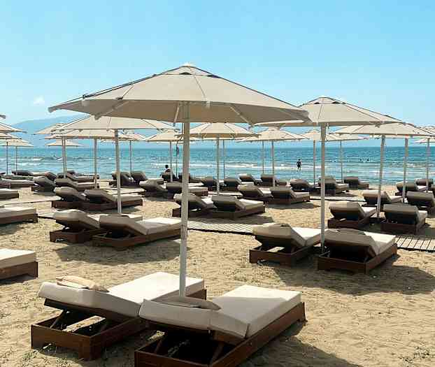 Solstolar och parasoller på en strand med havsvy. (AI-genererad text)