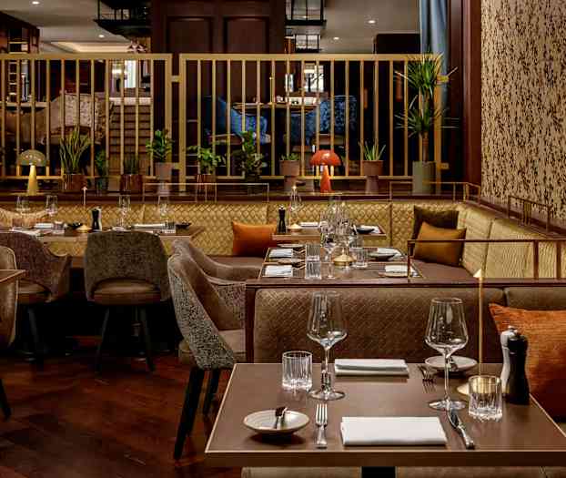 En modern restaurang med dukade bord, soffor och stolar, dekorerad med växter och bekväma detaljer. (AI-genererad text)