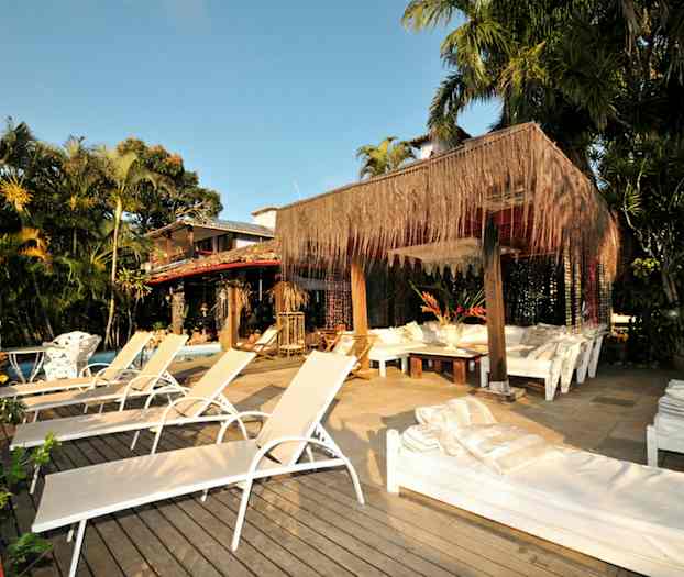 Solstolar och sittplatser under ett tak dekorerat med växter, omgivna av träd och växtlighet. (AI-genererad text)