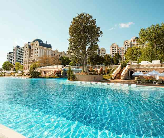 Stor utomhuspool framför ett hotell med klassisk arkitektur. (AI-genererad text)