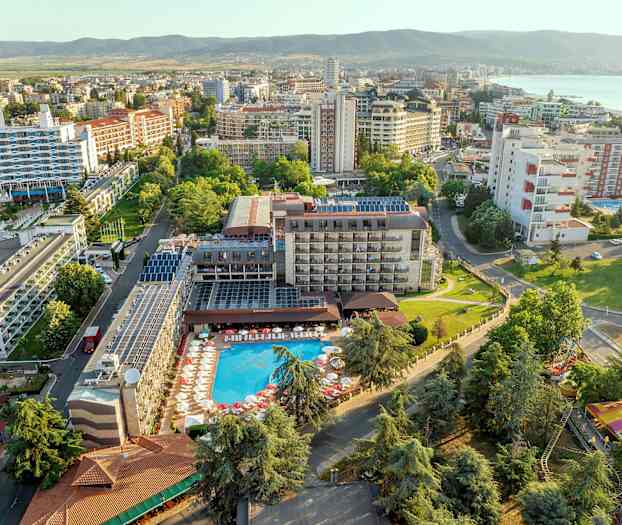 Flygvy av ett hotell med pool och omgivande byggnader i grönskande område. (AI-genererad text)