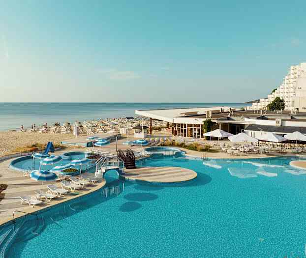 En bild av en pool, solstolar, och parasoller vid ett hotell nära en sandstrand. (AI-genererad text)