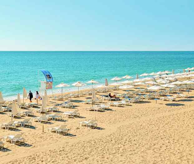 En strand med solstolar och parasoller nära havet. (AI-genererad text)