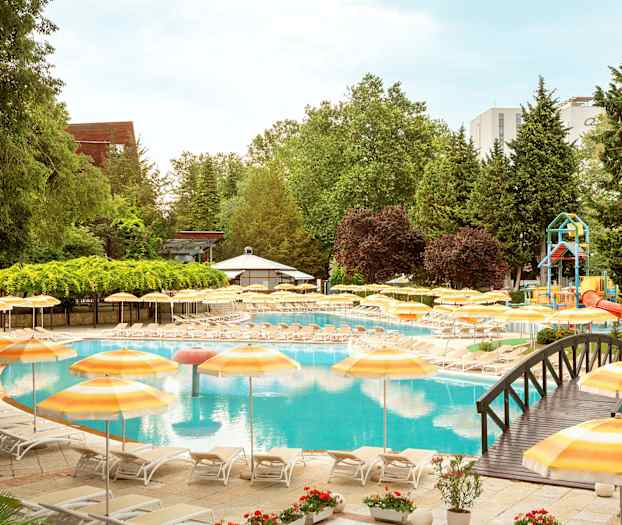 Poolområde med solstolar och gula parasoller, omgivna av grönska. (AI-genererad text)