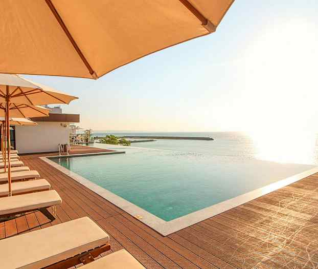 Poolområde med solstolar och parasoller, med utsikt över havet. (AI-genererad text)