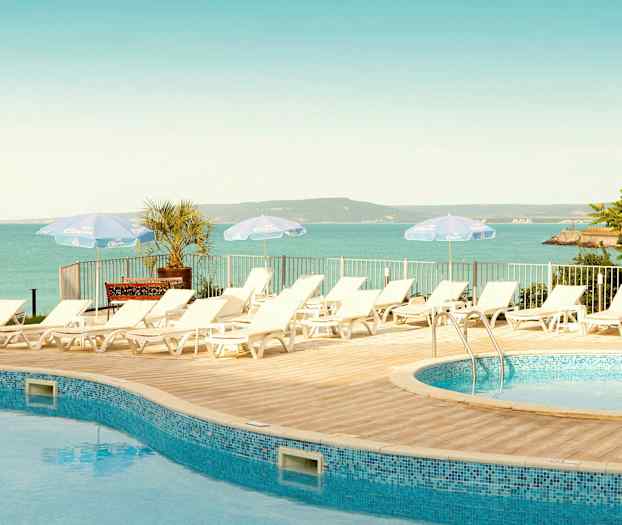 Solstolar vid en pool med utsikt över havet och landskapet. (AI-genererad text)