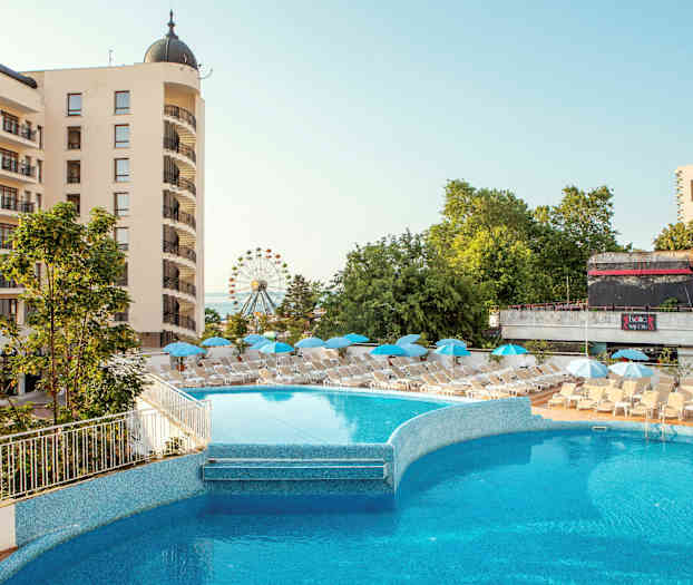 Hotellbyggnad med balkonger, en utomhuspool och solstolar med parasoller. Bakgrunden visar gröna träd och ett pariserhjul. (AI-genererad text)