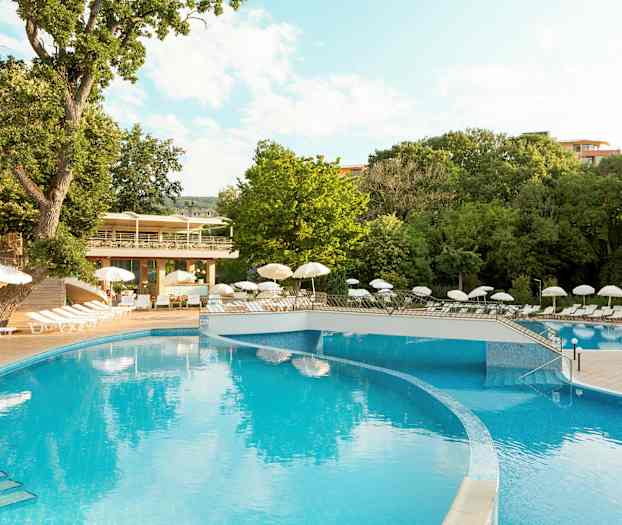 Utomhuspool med omgivande solstolar och paraplyer, omgiven av gröna träd. (AI-genererad text)