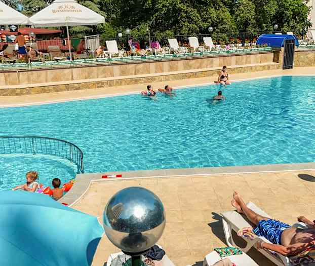 Utomhuspool med människor som badar och solar. (AI-genererad text)