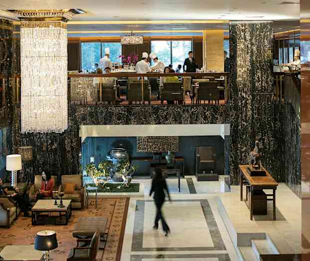 Hotellobby med eleganta möbler, stora fönster och en stor kristallkrona som hänger från taket. (AI-genererad text)