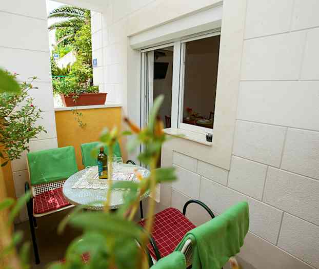 En uteplats med bord, gröna stolar och fönster till ett rum. (AI-genererad text)