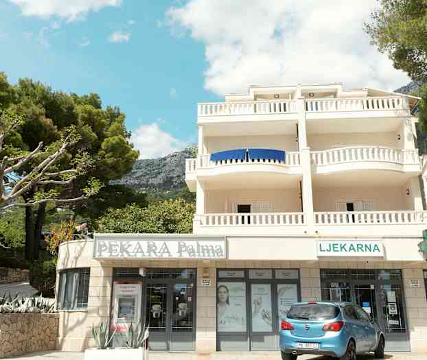 Byggnad med balkonger och butiker vid bottenvåningen. (AI-genererad text)