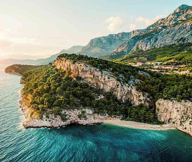 En kustlinje med branta klippor, en skog och klarblått hav. (AI-genererad text)