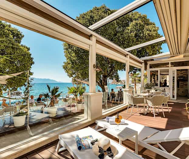 En terrass med sittplatser, solstolar och utsikt över havet. (AI-genererad text)