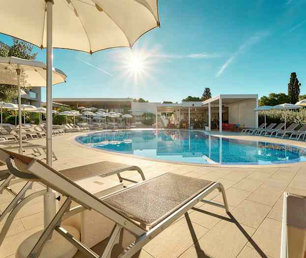 En utomhuspool omgiven av solstolar och parasoller under en klarblå himmel. (AI-genererad text)