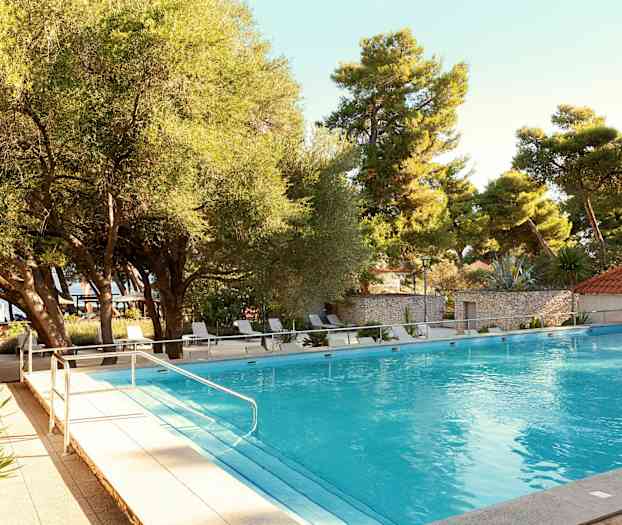 En utomhuspool omgiven av träd och solstolar. (AI-genererad text)