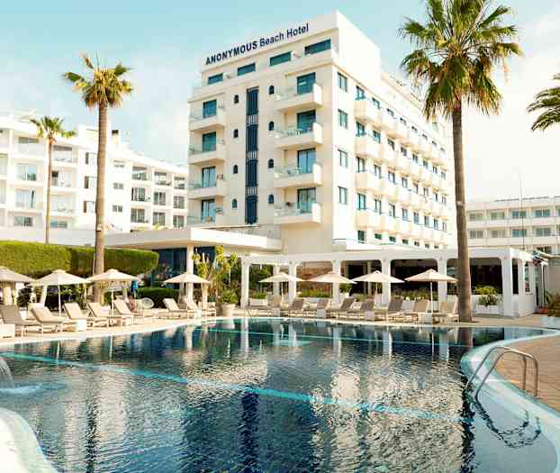 Hotell med pool, solsängar och parasoll i förgrunden. (AI-genererad text)