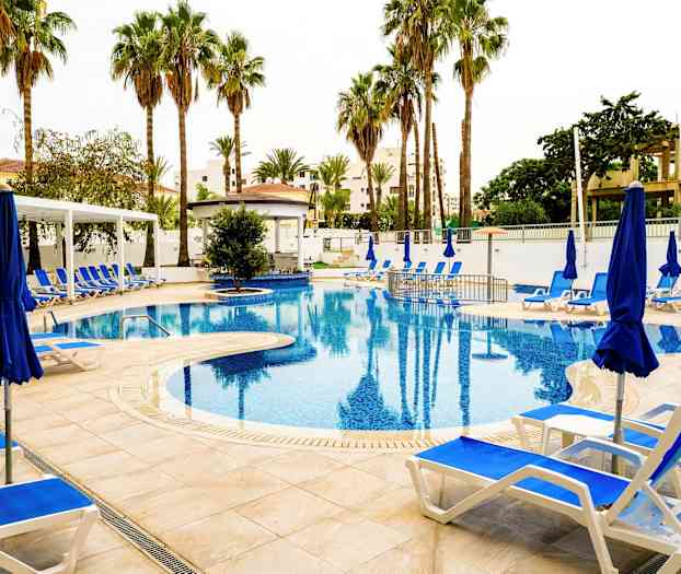 Bild av en utomhuspool omgiven av solstolar, blå parasoller och palmer. (AI-genererad text)