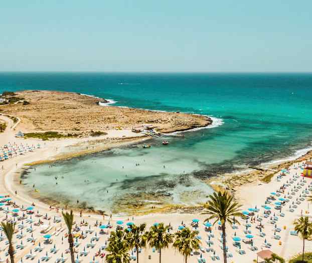 Sandstrand med parasoll och badande människor vid havet. (AI-genererad text)