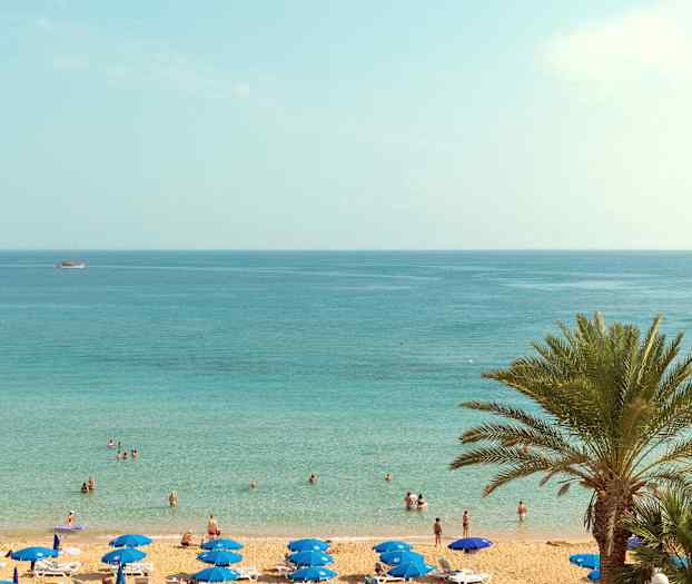 En strand med parasoller och människor vid vattnet. (AI-genererad text)