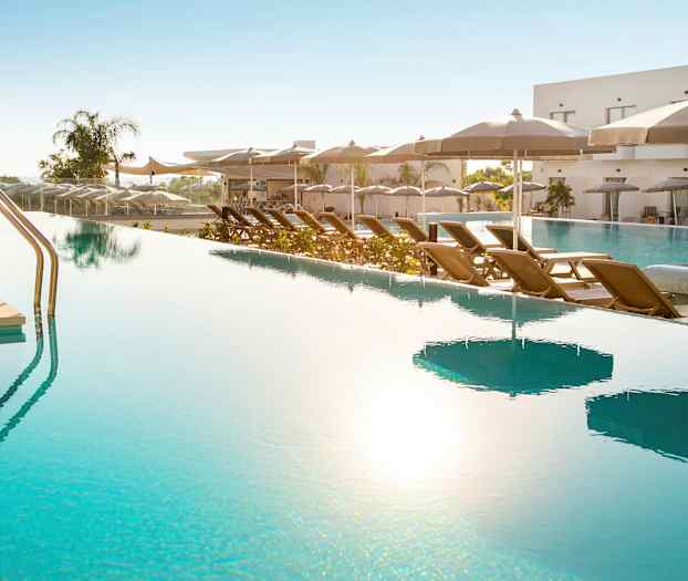 En utomhuspool med solstolar och parasoller vid sidan. (AI-genererad text)