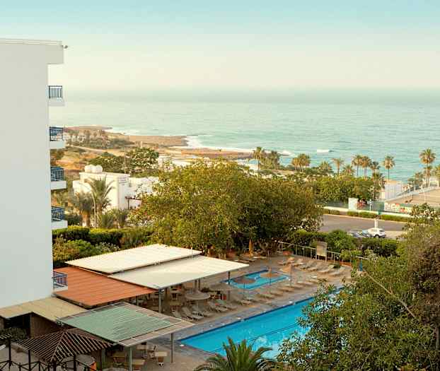 Hotellområde med pool, solstolar och havsutsikt. (AI-genererad text)