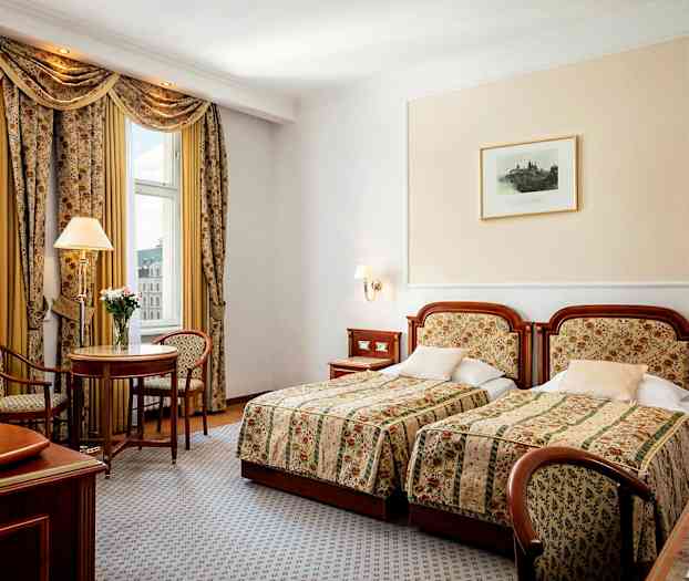 Ett hotellrum med två enkelsängar, ett litet bord med två stolar och fönster med utsikt. (AI-genererad text)