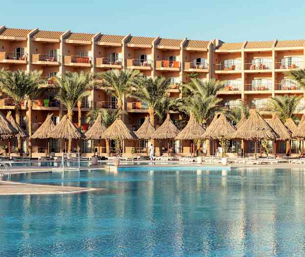 En hotellbyggnad med balkonger, framför en pool och palmer. (AI-genererad text)