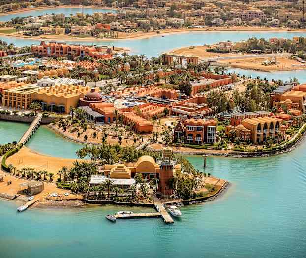 Flygfoto av en resort vid turkosa kanaler med båtar och palmträd. (AI-genererad text)