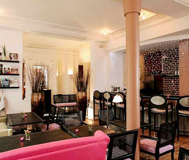 Ett inredd café- eller hotelllounge med bord, stolar och dekorationer. (AI-genererad text)