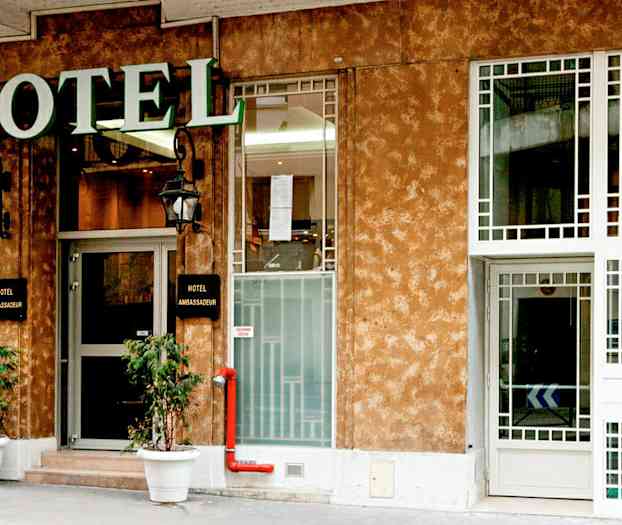 Framsidan av ett hotell med en skylt som säger 'Hotel Ambassadeur'. (AI-genererad text)