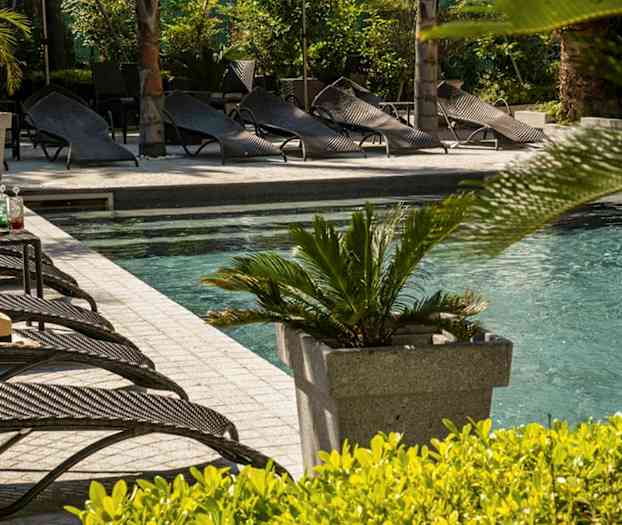 En utomhuspool med solstolar och växter i närheten. (AI-genererad text)