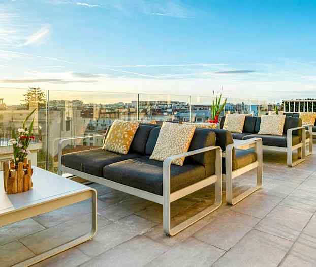 Möblerad takterrass med utsikt över staden och solnedgången. (AI-genererad text)