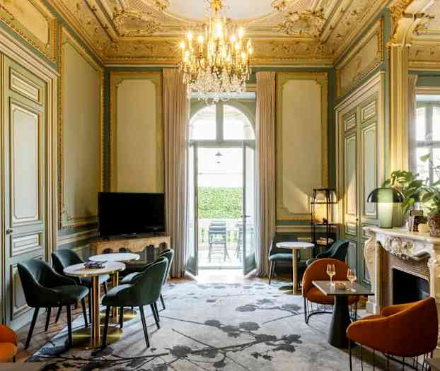 Ett elegant möblerat rum med dekorerat tak, sittgrupper och en ljuskrona. (AI-genererad text)